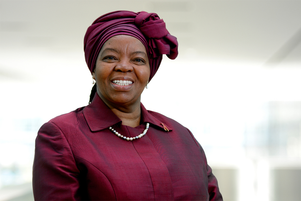 Sheila Tlou, a professor, nurse, HIV prevention advocate, artist, and Botswana's former minister of health, wearing a maroon headwrap and matching top.